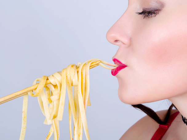 Nuori seksikäs nainen punaiset huulet syö spagettia kiinalainen syömäpuikot lähikuva
 - Valokuva, kuva