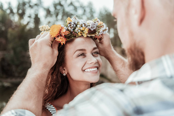 Beautiful green-eyed woman feeling extremely happy receiving nice floral chaplet - Φωτογραφία, εικόνα