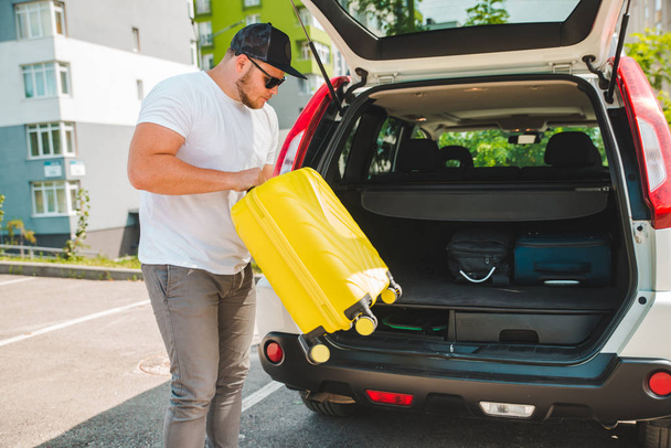 man putting bags in car trunk. ready for car travel. sunny morning - Fotografie, Obrázek
