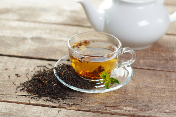Filiżankę czarnej herbaty z mięty pozostawia na drewnianym stole - Zdjęcie, obraz