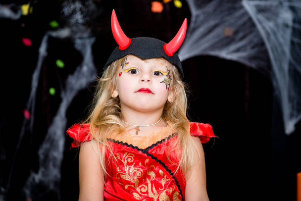 Bir çocuk, bir süpürge bir cadı şeklinde küçük bir kız örümcek ağları, kabak ve sonbahar yaprakları toplayan fonunda bir Cadılar Bayramı tatil pozlar.. - Fotoğraf, Görsel
