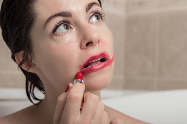 női depresszió. egy nő a fürdőszobában egy megkövesedett pillantást vágás rúzs az arcán. - Fotó, kép