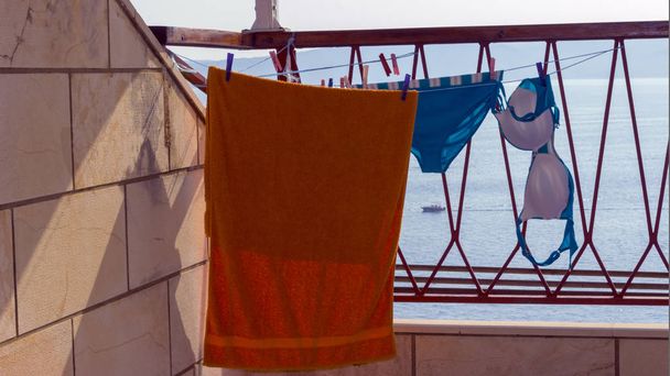 A női fürdőruha és törölköző a tengerre néző erkély szárítási. - Fotó, kép