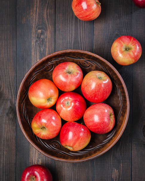 Red apples on a dark rustic background in a clay bowl.  Flat lay. - Foto, Bild