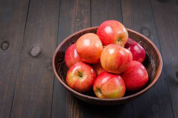 Red apples on a dark rustic background in a clay bowl.  Flat lay. - Foto, Bild