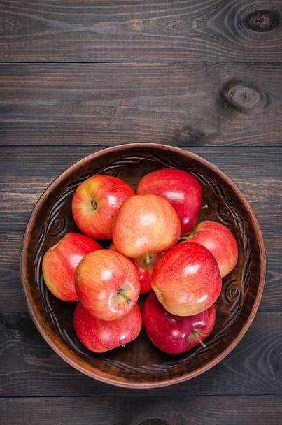 Red apples on a dark rustic background in a clay bowl.  Flat lay. - Фото, зображення