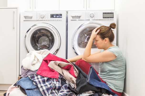 Smutna kobieta siedzi w pokoju pranie brudnych ubrań - Zdjęcie, obraz