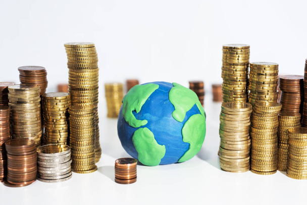 Una gran cantidad de monedas en la mesa blanca con el modelo de la Tierra. Foto abstracta del dinero
. - Foto, Imagen