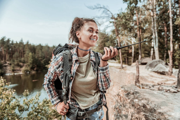 Happy woman wearing short denim shorts feeling happy hiking with backpack - Foto, Imagen
