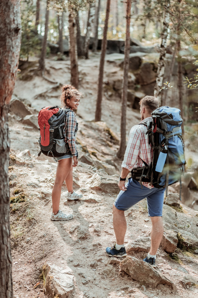 Couple of backpackers wearing squared shirts and sneakers enjoying hiking trail - Photo, Image