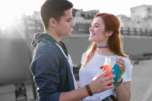 Young couple enjoying tasty cocktails and standing with glass bottles - Foto, immagini