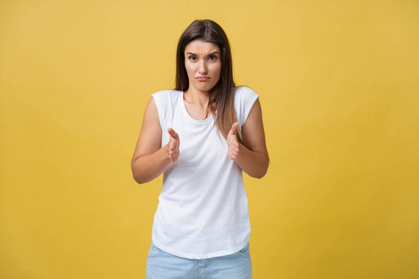 Πορτρέτο απογοητευμένος αμήχανη ελκυστική γυναίκα σε άσπρο πουκάμισο, αυξάνοντας το χέρι και τη διαμόρφωση μικρό στοιχείο, κοιτάζοντας τα δάχτυλα και frowning από αντιπαθούν και λύπη, στέκεται πάνω από το κίτρινο φόντο - Φωτογραφία, εικόνα
