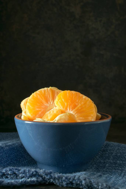 テキストのコピー スペースで暗い素朴な背景にオレンジ タンジェリン · セグメントの青いボウル - 写真・画像