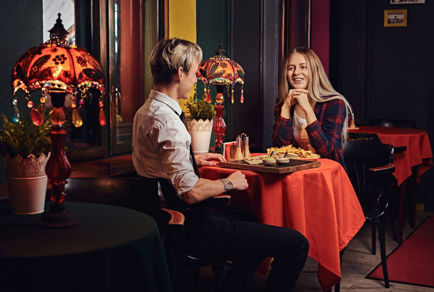 Atrakcyjna, Młoda para rozmowy i jedzenie nachos podczas randki w meksykańskiej restauracji.  - Zdjęcie, obraz