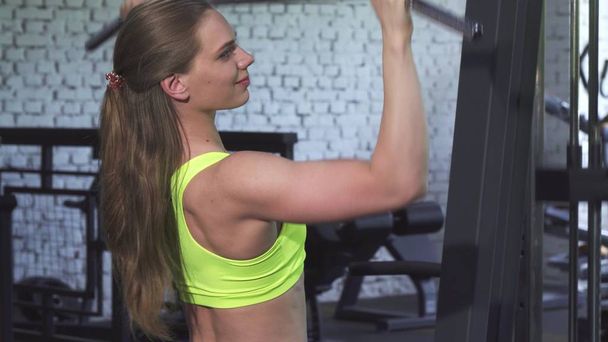 Attractive athletic woman exercising on lat pulldown cable gym machine - Photo, Image