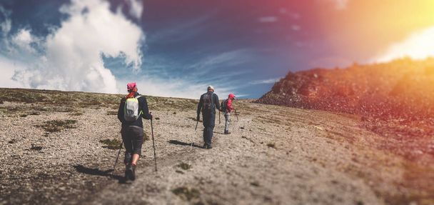 Reizen bestemming ervaring Lifestyle Concept concept. Team van reizigers met rugzakken en trekking stokken klimt de berg - Foto, afbeelding
