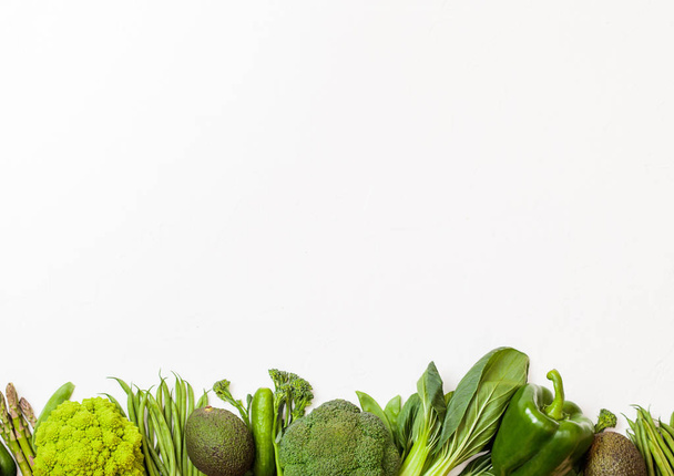 Assorted green toned raw organic vegetables on white background. Avocado, cabbage, broccoli, cauliflower and cucumber with trimmed and mung beans, pak choi, loose pepper and lettuce - Photo, Image