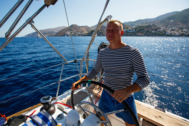 Young man at the helm of a sailing yacht boat. - Foto, Imagem