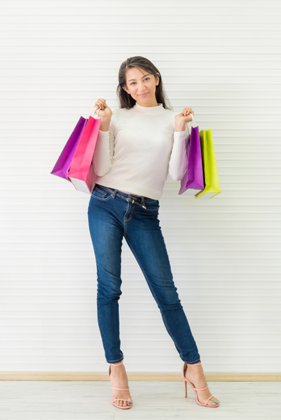 Donna felice con colorata shopping bag su sfondo bianco parete
 - Foto, immagini