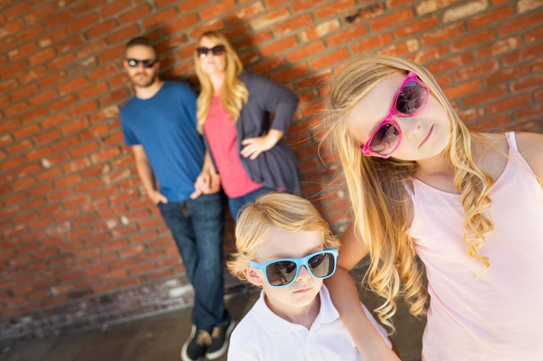 mignon jeune caucasien frère et soeur portant lunettes de soleil avec parents derrière
. - Photo, image