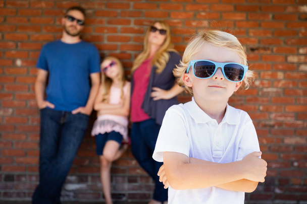 lindo joven caucásico chico usando gafas de sol con familia detrás
. - Foto, Imagen