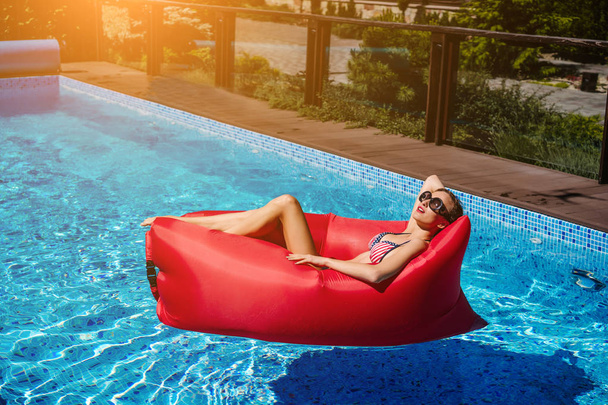 kobieta na czerwony leżaku w basenie - Zdjęcie, obraz