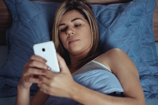 Women are using the smart phone on the bed before she sleeping at night. Mobile addict concept. - Zdjęcie, obraz