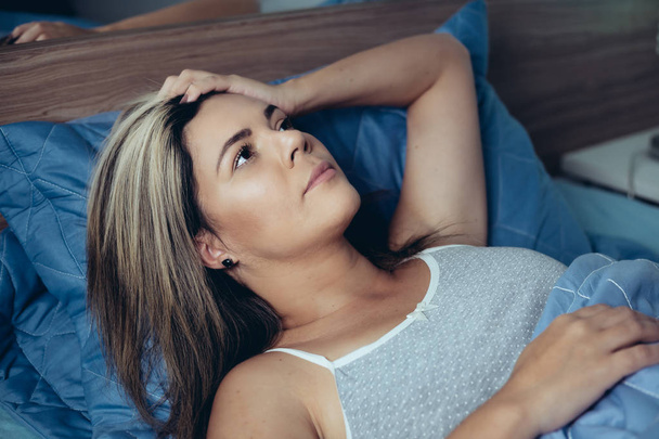 Sleep disorder, insomnia. Young blonde woman lying on the bed awake - Φωτογραφία, εικόνα