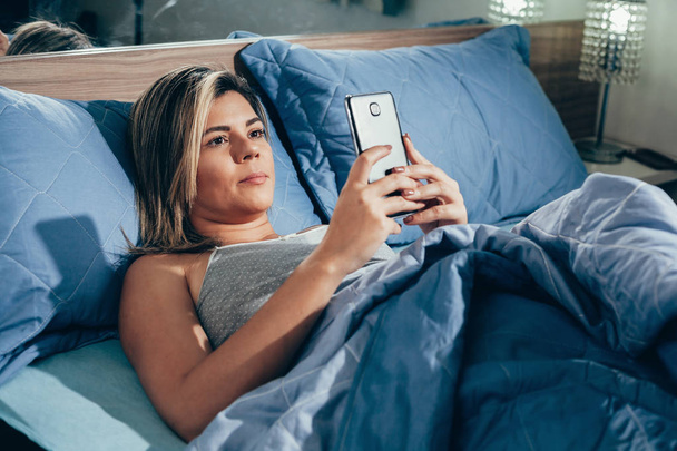 Women are using the smart phone on the bed before she sleeping at night. Mobile addict concept. - Фото, изображение