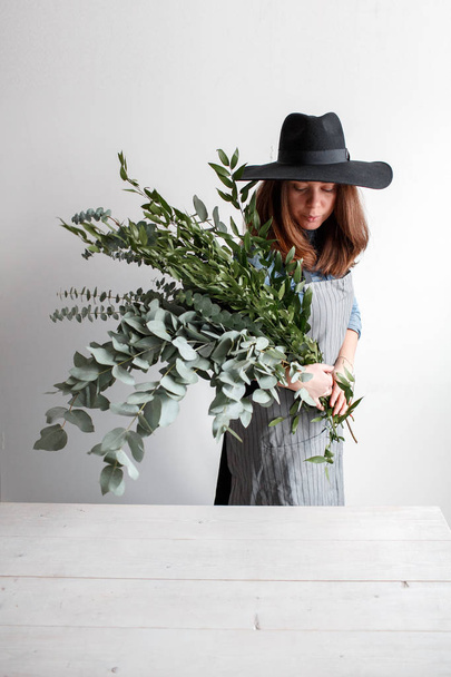 Florist makes a bouquet. Process of work. woman holding a bouquet of eucalyptus in hands - Photo, image