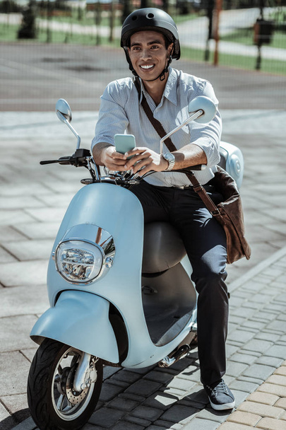 Happy male student waiting for call on motorbike - Foto, Imagen