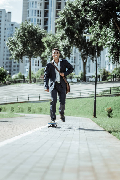 Pleasant male student rushing fast on skateboard - Photo, Image