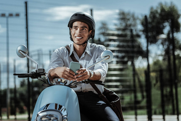 Sincere optimistic guy reconsidering answer on motorbike - Foto, immagini