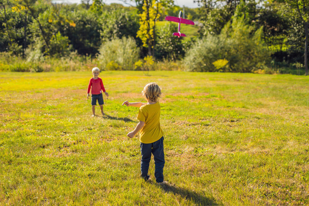 Two happy boys playing with toy plane in park - Фото, зображення