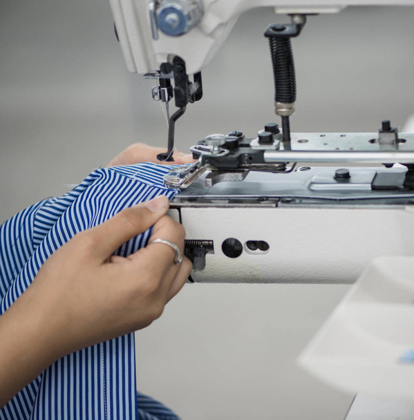 the woman in the workshop sews buttons to the shirt - Фото, зображення