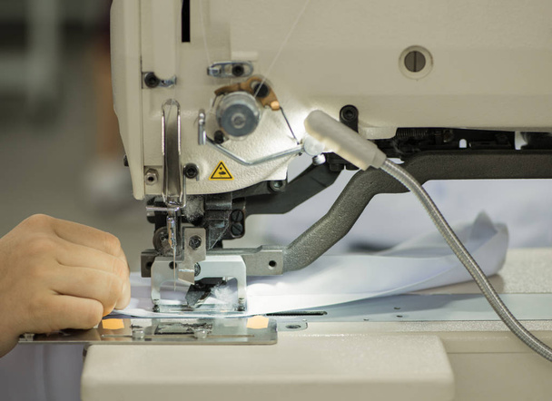 costureira em uma máquina de costura faz uma camisa na oficina de costura. a mulher na máquina costura o colarinho e algemas
 - Foto, Imagem