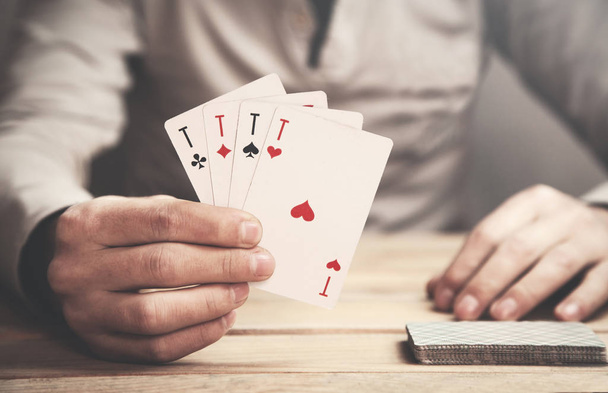 Homme montrant des cartes à jouer sur une table en bois
. - Photo, image