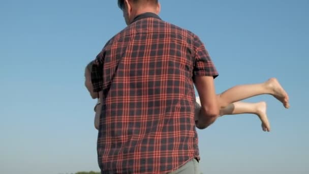 Close-up of father and daughter playing together. A young father is spinning his daughter at the beach of the sea shore super slow motion - Footage, Video