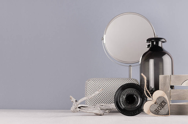 Fashion modern monochrome style in bathroom interior - cosmetic products and accessories, black glass vase with flowers, heart home, circle silver mirror, old snag on white wood board and grey wall. - Foto, Imagem