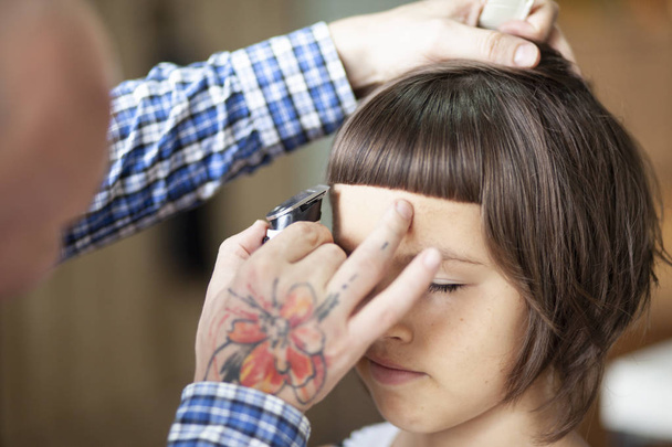 парикмахер стрижет волосы маленькой девочки в салоне красоты, крупным планом
  - Фото, изображение