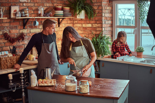 Mom dad and little daughter together cooking breakfast in loft style kitchen. - Photo, Image