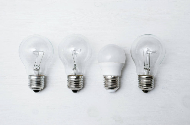 Light bulbs isolated on the white wooden table surface background. - 写真・画像