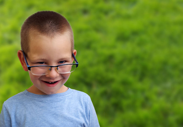 Чарівний маленький хлопчик дивиться над окулярами і посміхається
  - Фото, зображення