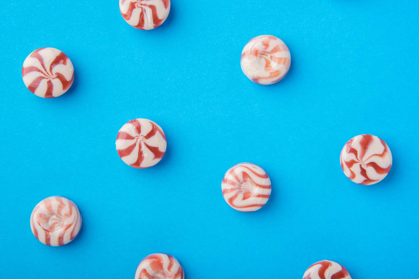 Červené kulaté candy karamel a bílá na modrém pozadí - Fotografie, Obrázek