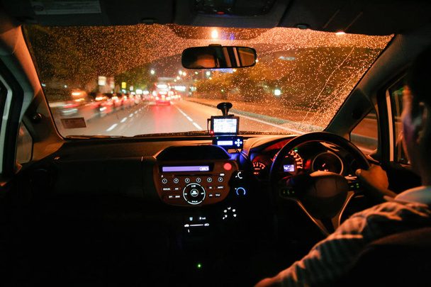 Guidare sotto la pioggia in una città di notte. Gocce di pioggia sul parabrezza
 - Foto, immagini