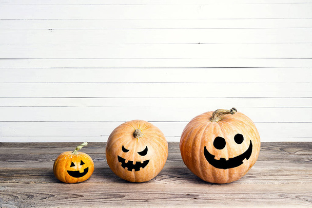 Halloween pumpkins with funny faces on a wooden table. Space for text. Halloween background. - Valokuva, kuva