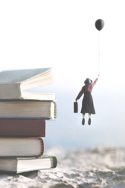 mujer llevada por un globo vuela por encima de una montaña de libros gigantes
 - Foto, Imagen