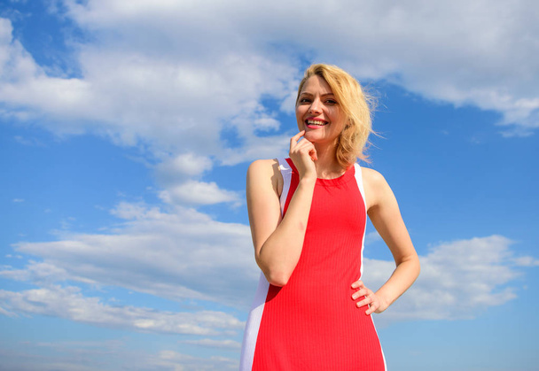 Girl blonde lady smiling enjoy warm sunlight blue sky with clouds background. Woman red dress feels carefree and free. Flirt and coquette concept. Girl playful mood coquette. Sunlight pleasant warm - Photo, image