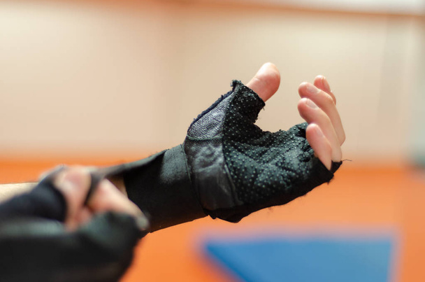 Sportsman is wearing fitness gloves in gym. - Photo, Image