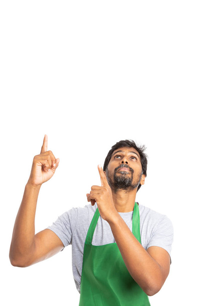 Hipermercado ou supermercado indiano empregado do sexo masculino apontando e olhando para cima na área de texto cópia para publicidade isolada em branco
 - Foto, Imagem